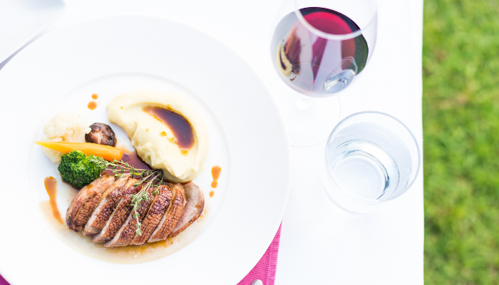A seared duck breast and a glass of red wine.
